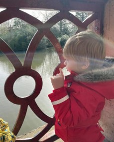 A young boy signing as he looks out of a window
