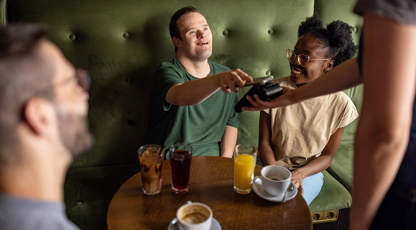 Young man and woman in a pub, he's paying with his mobile